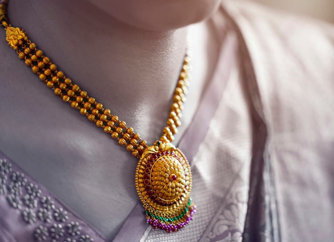 Luxurious gold necklace with intricate traditional patterns and ruby gemstones
