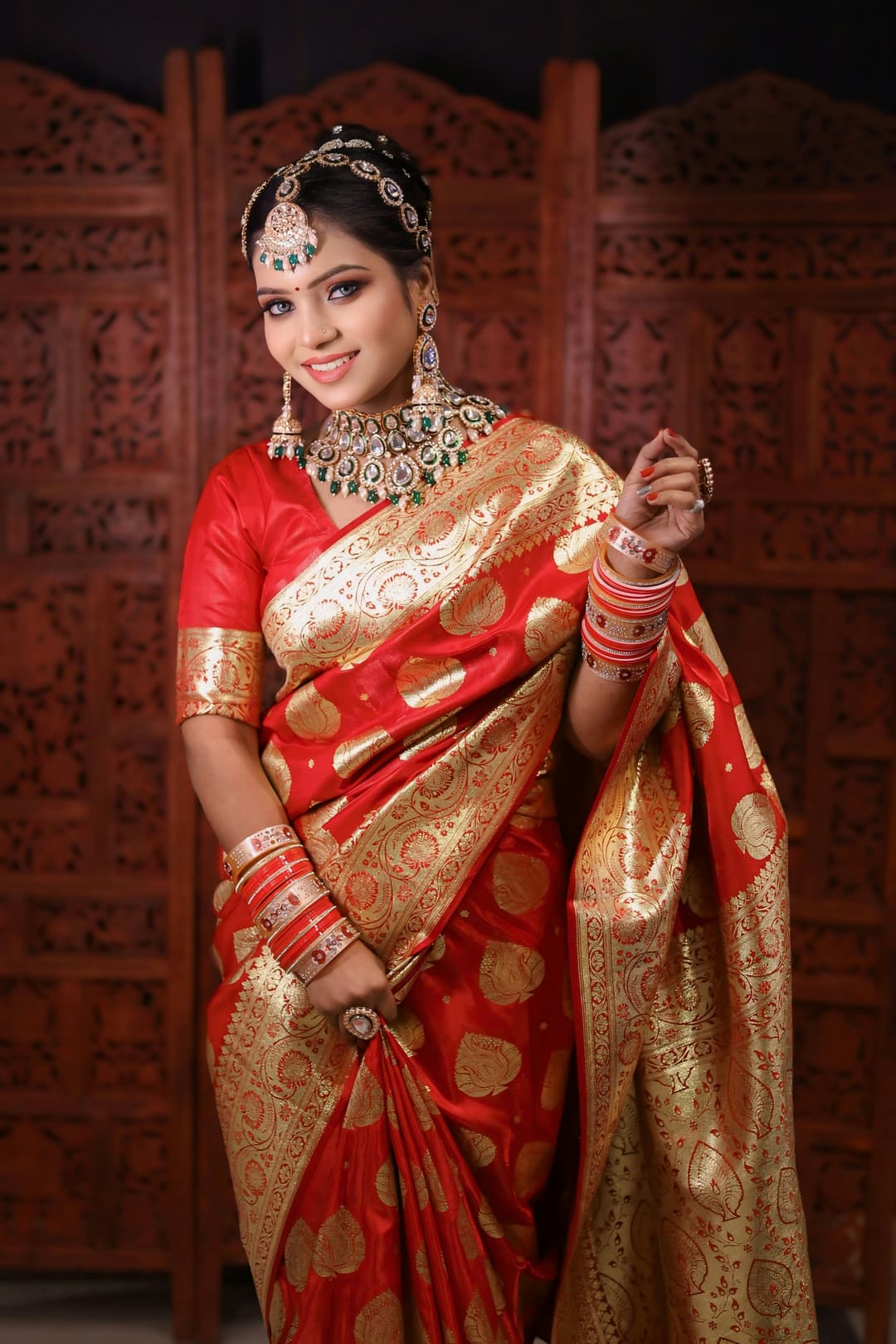 Smiling Indian woman in traditional red saree wearing gold jewelry at wedding ceremony